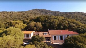 A two-story house with a red-tiled roof, surrounded by dense forest and a hill in the background. - Close to the beaches, spacious, air conditioning, panoramic view of the gulf!  (OLMETO)