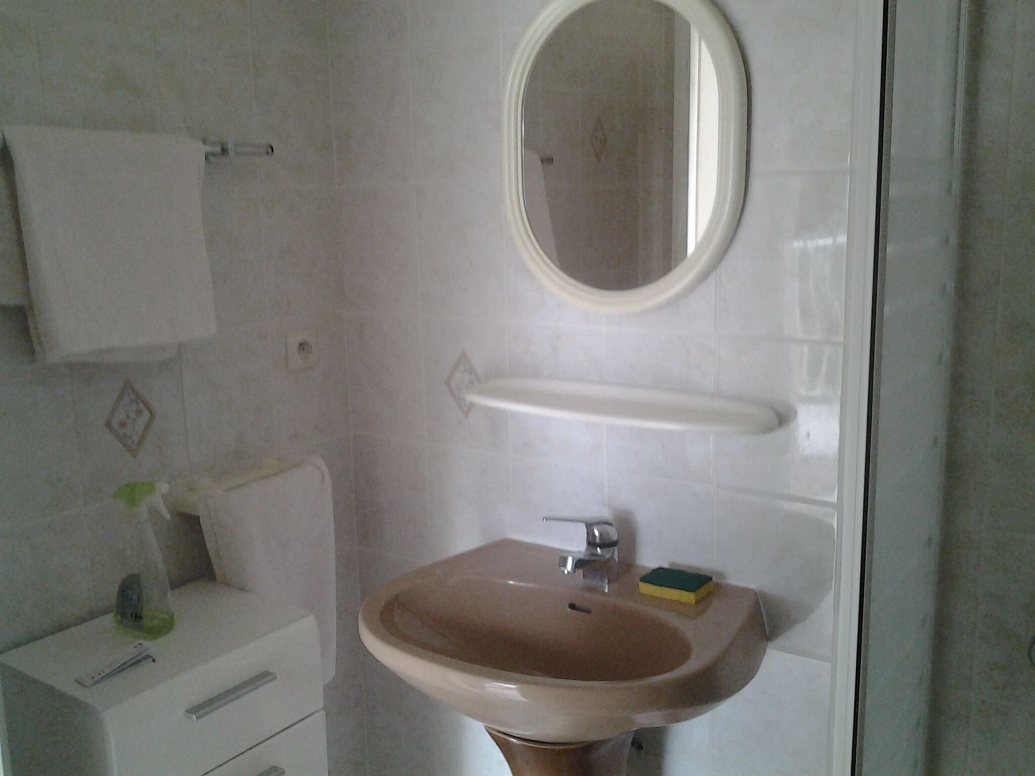 A bathroom with a sink, mirror, towel rack, and a small shelf with a soap dish.