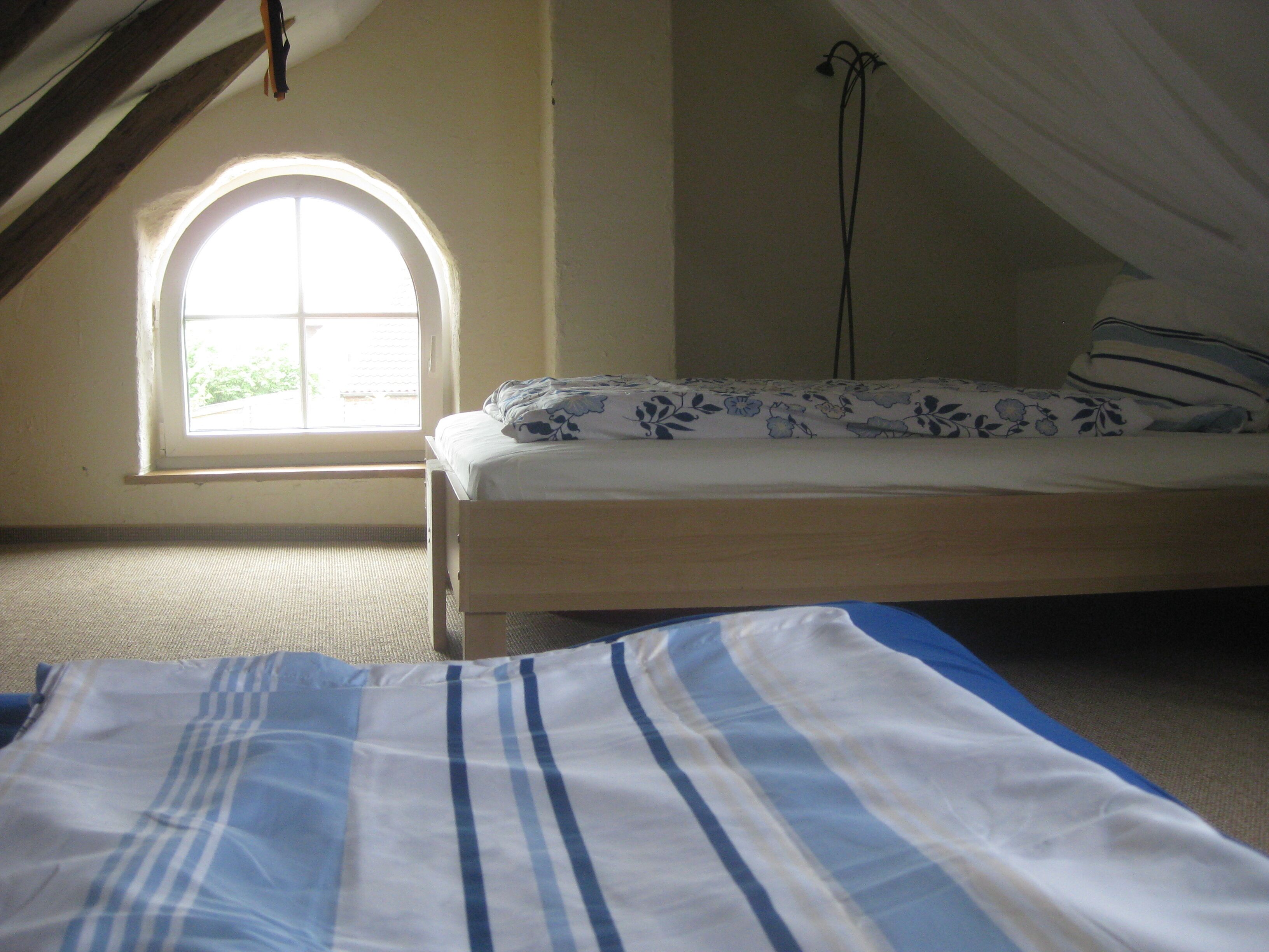A bedroom with a single bed, a window with a view, and a sloped ceiling.