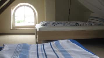 A bedroom with a single bed, a window with a view, and a sloped ceiling.