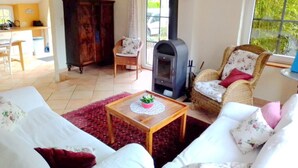 Un salon chaleureux avec une cheminée, un coin repas et une vue sur la verdure environnante.