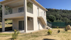 Un bâtiment à deux étages doté d’un balcon, d’une terrasse couverte et offrant une vue sur un paysage vallonné.