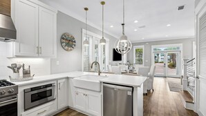 A modern kitchen with white cabinetry, stainless steel appliances, and pendant lighting. - Coastal Pet-Friendly Home w/ Brand New 1st Floor Deck | Near Lagoon Pool & Beach (Panama City Beach)