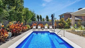 A rectangular swimming pool with clear blue water, surrounded by a concrete deck. There are white lounge chairs aligned along the pool's edge. - The Witton Yarrawonga - Spring Offer (Yarrawonga)
