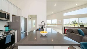 Una cucina moderna con elettrodomestici in acciaio inossidabile, un'isola centrale con una vasca e vista sull'area soggiorno.