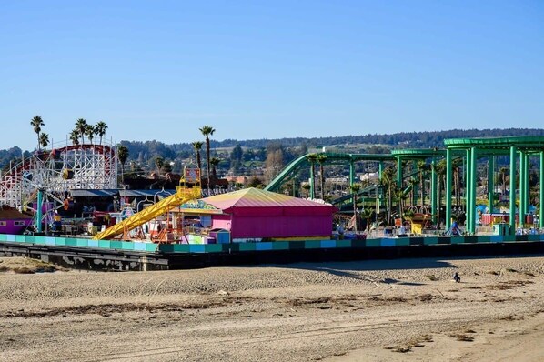 A beachside amusement park with rides and a large pink building.