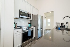 A modern kitchen with white cabinets, stainless steel appliances, and a black countertop. - Giant Dipper House near the Boardwalk (Santa Cruz)