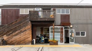 Un edificio con una rampa in legno che conduce a una porta con la scritta 'SERVE'.