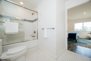 A modern bathroom with a glass-enclosed shower, a white toilet, and a tiled floor.