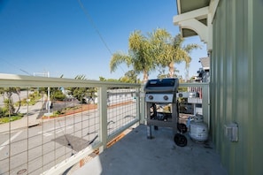 Un balcon équipé d’un barbecue, d’un chauffe-eau et d’une bouteille de propane.