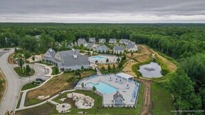 Ett flygbildsfoto av ett bostadsområde med flera hus, en stor swimmingpool och en liten damm.
