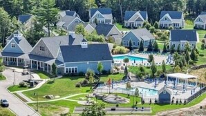 Ett bostadsområde med flera hus, en swimmingpool och en välskött gräsmatta.
