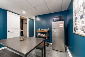 A compact kitchen with a dark countertop, a stainless steel refrigerator, and a blue wall. - Cozy, Affordable, Luxurious | Central Location (Indianapolis)