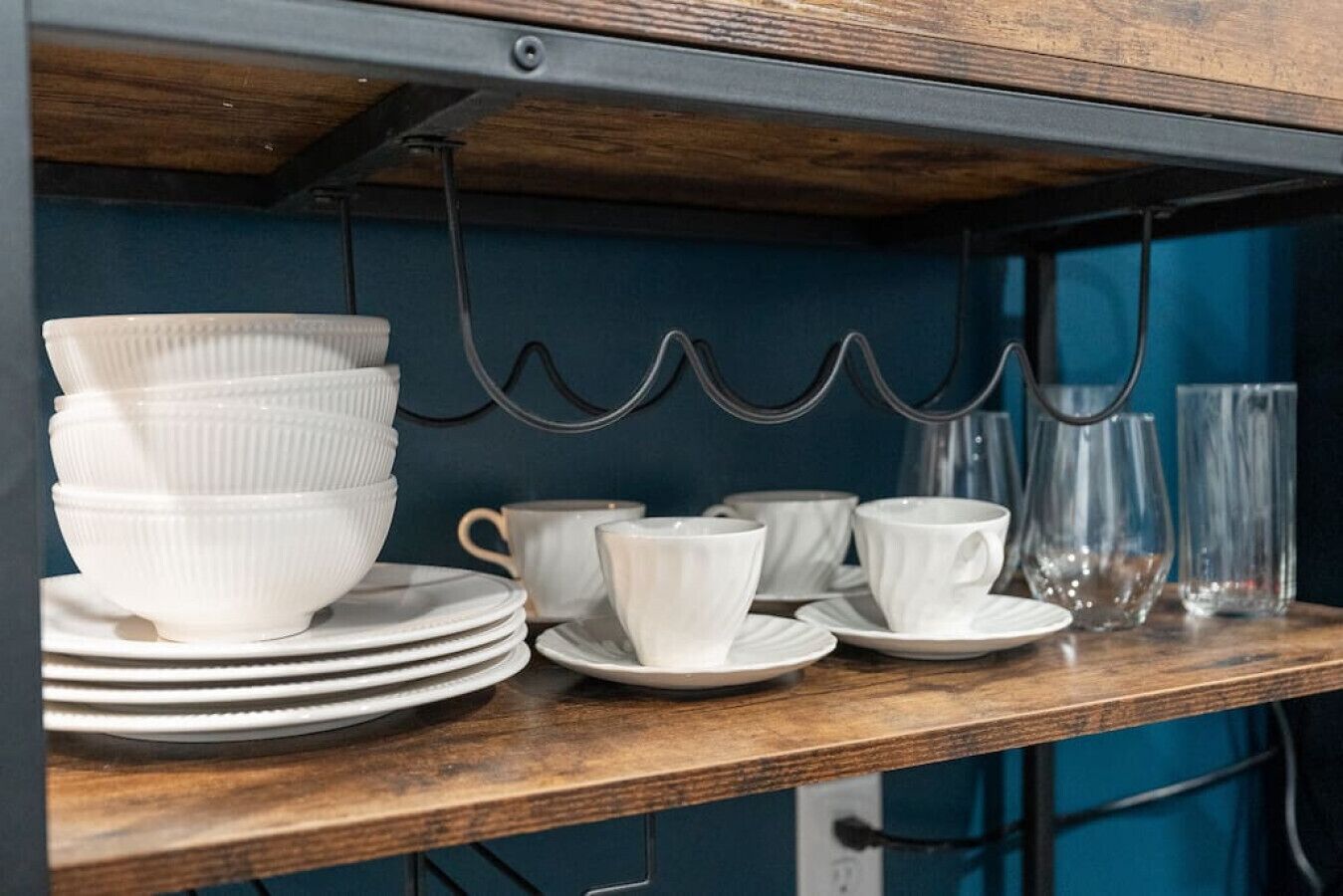A kitchen counter with stacked white bowls, plates, and a coffee maker.