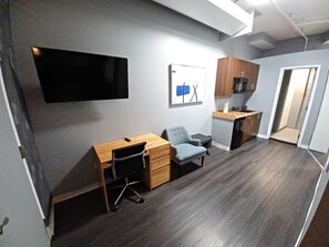 A modern office space with a desk, chair, and a flat-screen TV mounted on the wall. - Experience Boston At It’s Finest! (Boston)
