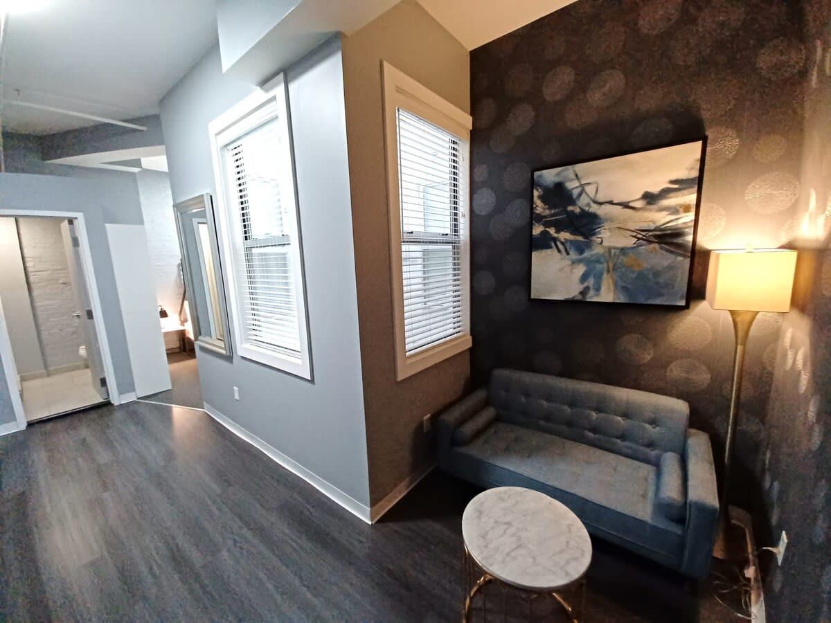 Un salon moderne avec un canapé gris, une table basse ronde et un tableau accroché au mur.