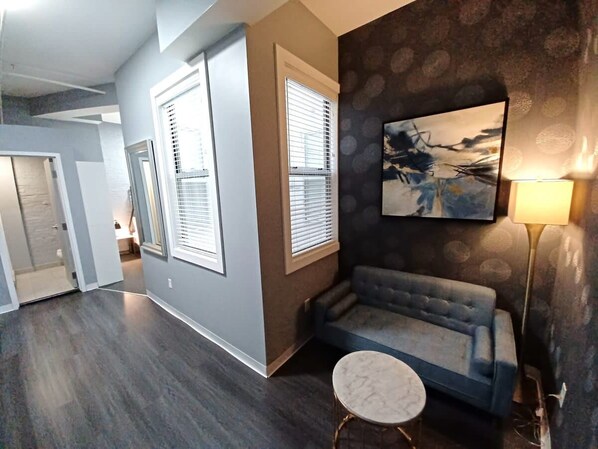 Un salon moderne avec un canapé gris, une table basse ronde et un tableau accroché au mur.