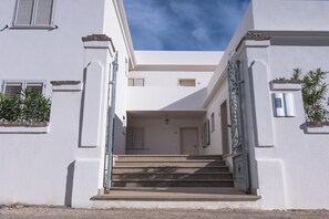 A building with a central staircase leading to a door, flanked by white walls and windows with shutters. - Le Residence del Golfo Orosei (Orosei (NU))