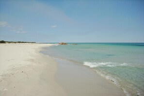 A beach with clear turquoise water, sandy shore, and distant rocky formations. - Le Residence del Golfo Orosei (Orosei (NU))