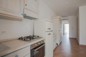 A kitchen with a gas stove, oven, and white cabinetry. - Le Residence del Golfo Orosei (Orosei (NU))