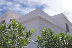 A white building with a triangular roof and arched windows.