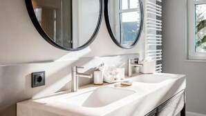 A modern bathroom with a double vanity, two large mirrors, a white sink, and a towel rack. - Clounys Hotel & Restaurant (Hamburg)