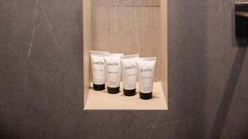 A bathroom with a wooden vanity and a shelf holding four bottles of Bablor products.