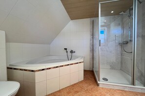 A bathroom with a bathtub, shower, and toilet.