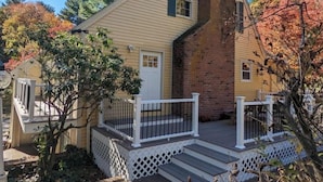 A two-story house with a front porch, a brick chimney, and a small deck. - Spacious vacation townhome unit with a pool (Weston)