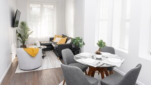 A modern living room with a sofa, coffee table, and a dining area with a table and chairs.