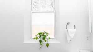 A bathroom with a white sink, a towel rack, and a potted plant by the window.