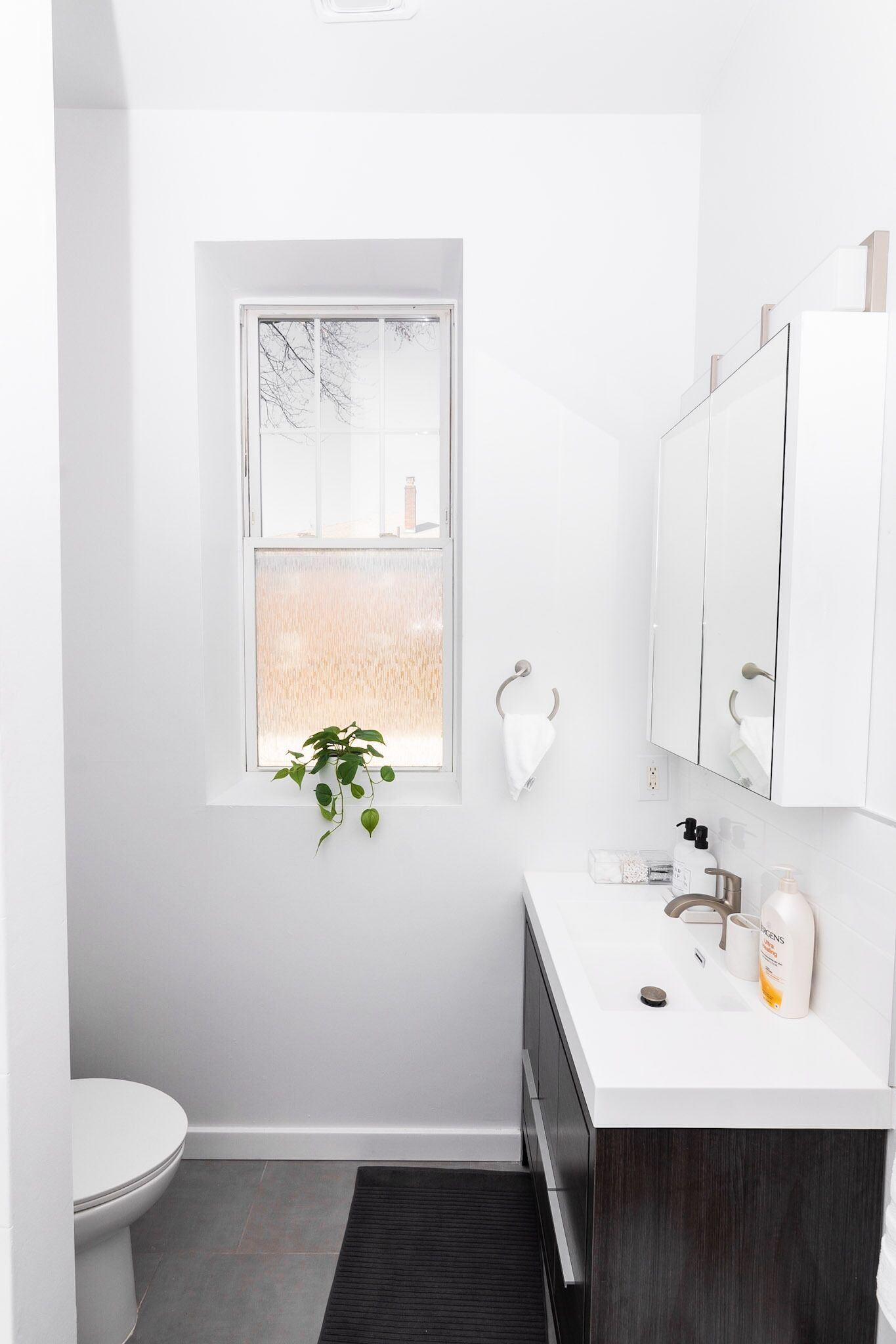 Un baño moderno con inodoro, lavamanos y ventana.