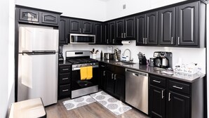 A modern kitchen with black cabinets, stainless steel appliances, and a white countertop.