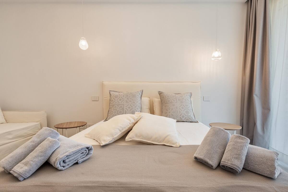 Quarto de hotel com cama, almofadas e toalhas.