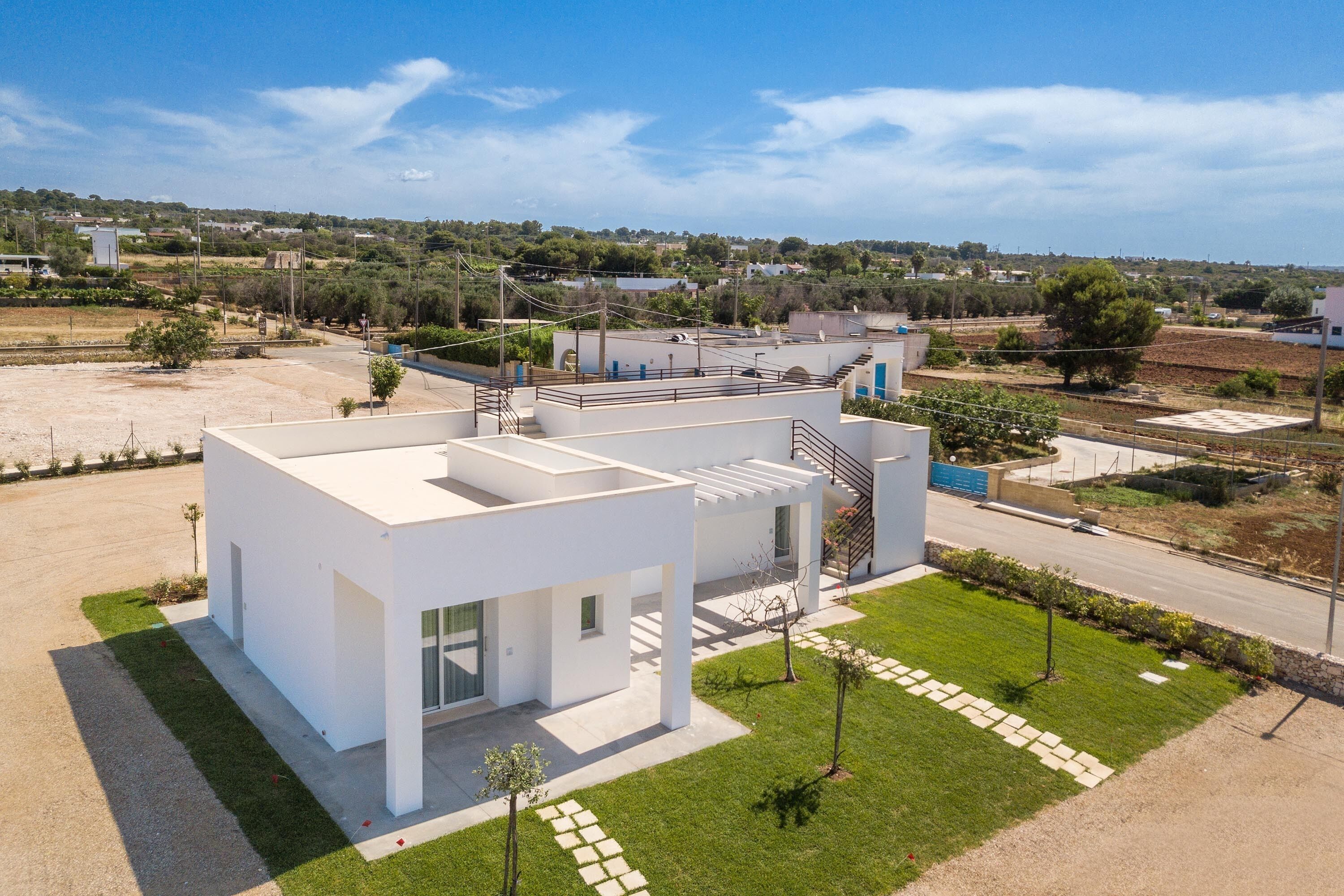A modern, white building with a flat roof and a spacious courtyard.
