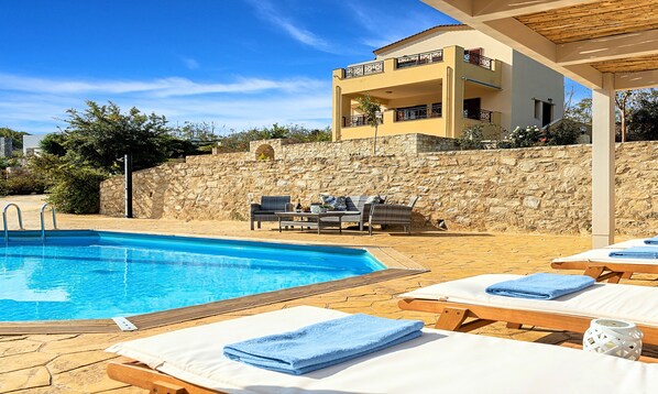 A pool area with lounge chairs and a stone wall.