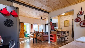 Una cocina moderna con suelo de madera, un refrigerador y una zona de comedor con mesa y sillas.