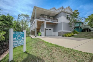 Une maison à deux étages avec un balcon, une véranda et un garage.