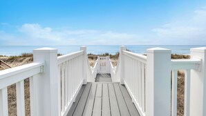 A wooden boardwalk leading to the beach with white railings. - The Sale Fish: Modern Oceanfront Home with Private Pool and Elevator (Oak Island)