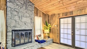 Una habitación con chimenea de piedra, techo de madera y puerta corrediza de vidrio.