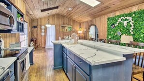 Una cocina con paredes de madera, una isla de mármol y un adorno verde en la pared.