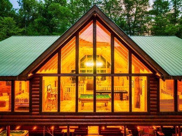 A log cabin with a large glass window, a pool table, and a cozy interior. - Custom Murals That Bring the Mountains to Life (sevierville)