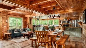 Interno di una baita in legno con angolo pranzo, cucina e ampie finestre.
