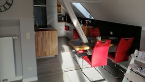 Een moderne keuken met witte kastjes, een houten aanrecht en een rode stoel.
