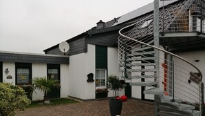 Een huis met een wenteltrap, een schotelantenne en een verharde oprit.