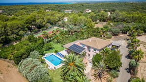 A residential property with a swimming pool, solar panels, and a tennis court surrounded by lush greenery and a view of the sea. - Finca near the beach Casa Bonita in Mallorca (Colònia de Sant Jordi)