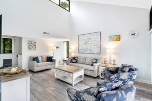 Ein geräumiges Wohnzimmer mit hoher Decke, großem Fenster und einem modernen Kamin.