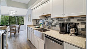Una cucina moderna con mobili bianchi, schienale piastrellato ed elettrodomestici in acciaio inossidabile.