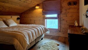 A cozy bedroom with a wooden ceiling, a bed with a white duvet, a window with a view, and a small table with a figurine. - 100m from ski slopes, 3rd floor, view panoramic, swimming pool, balcony, parking, tv, ski locker (Villard-sur-Doron)