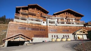 A multi-story building with wooden balconies and a garage. - 100m from ski slopes, 3rd floor, view panoramic, swimming pool, balcony, parking, tv, ski locker (Villard-sur-Doron)